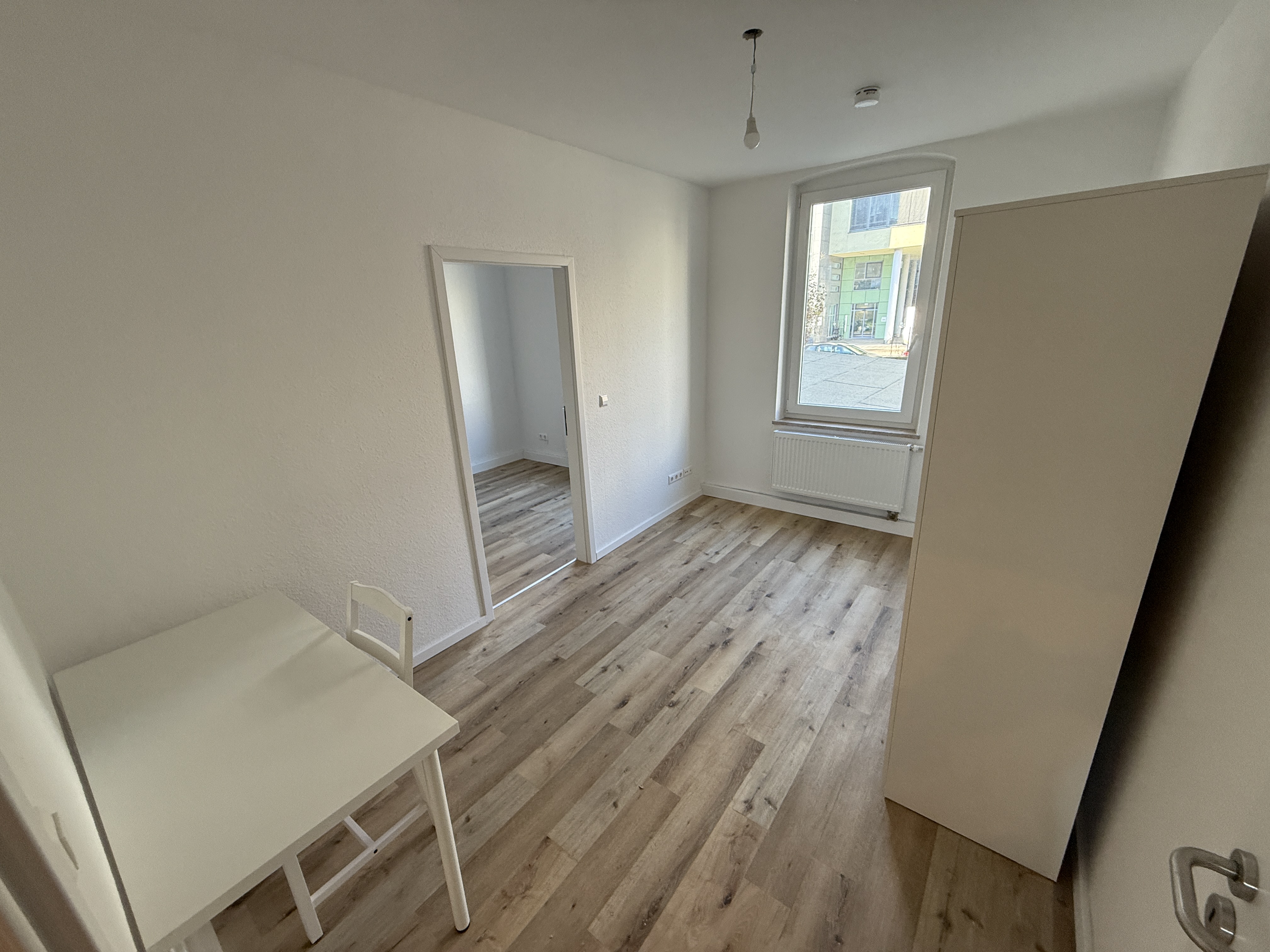Zimmer mit Schreibtisch und Durchgang zum Nebenzimmer