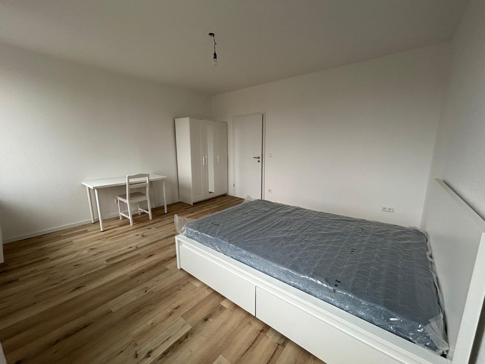 Zimmer mit Doppelbett, Kleiderschrank und Schreibtisch