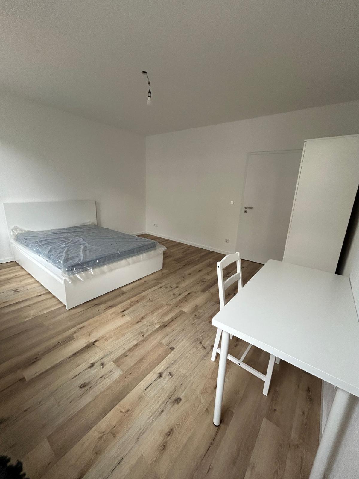 Zimmer mit Bett und Schreibtisch